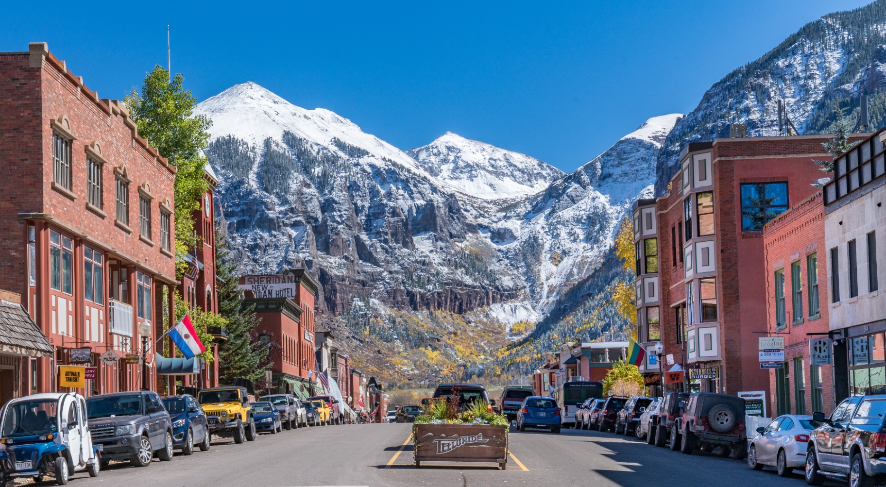 Main street of Telluride with snow-capped mountains rising at the end of the box canyon
